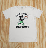 Cream Comfort Colors tee with retro cartoon in green shorts holding a horseshoe with black text.